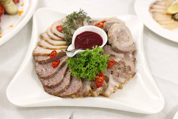 Fresh butcher cut meat assortment garnished with fresh vegetables and aromatic herbs.