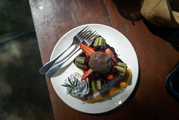 A beautifully presented dessert featuring a variety of fresh fruits, rich chocolate ice cream, and whipped cream, perfect for any food lover's indulgence.