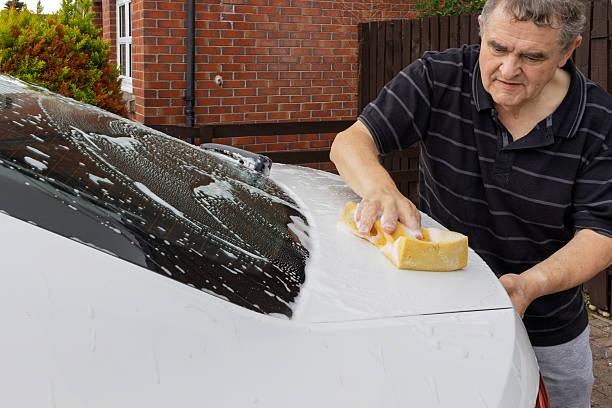 istock Man washing boot lid of white hatchback car with soapy yellow sponge 2227409437