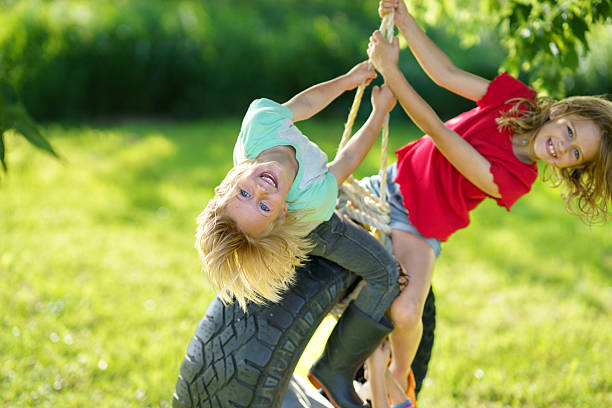 Fun and laughter on a warm sunny day as happy kids play on a swing outdoors.