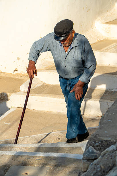Tholaria, Amorgos, Greece, July 15th 2025, An elderly man walks up stairs with his cane in the ancient city of Tholaria greece.