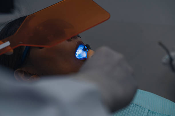 istock Asian dentist conducting a blue light based oral procedure for a patient 2227410515