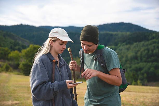 Young people in mountains with backpack travel using phone to check for location
