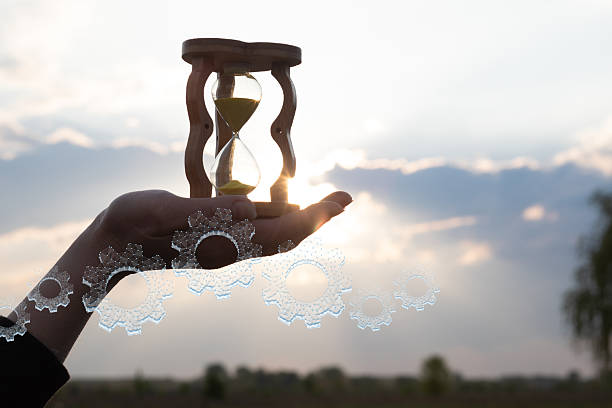 istock Holding time in an hourglass against sunset 2227412453