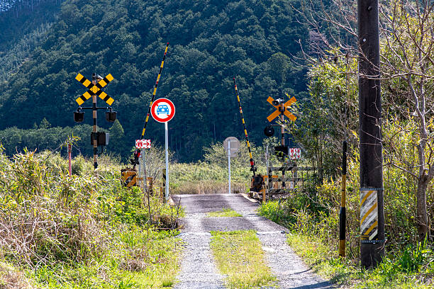 Railway crossing in rural Kitamuro District, Mie, Japan on a dirt road and surrounded by green grassen mountains with trees in background