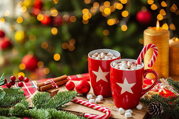 istock Hot chocolate marshmallow mug on Christmas decorated table near illuminated Christmas tree. Holidays or December season. Cozy atmosphere with ornaments and burning candles. Sweet food for Christmas 2227418383