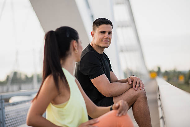 istock Athletic couple looking at each other during leg stretch 2227419719