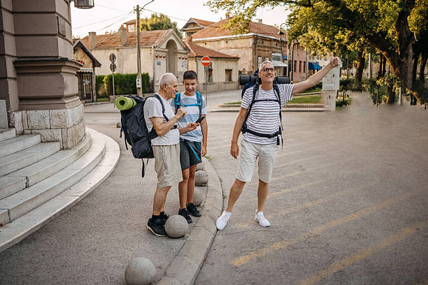 Grandfather, father and son traveling together with backpacks as a tourists in the city standing in front of public building on sidewalk