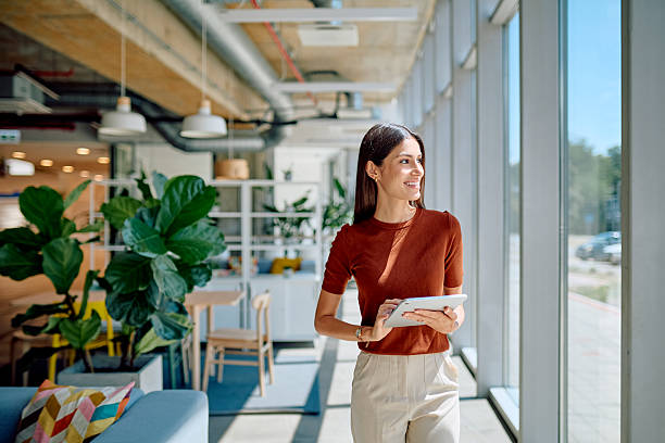 istock Businesswoman walking in modern office using digital tablet and looking outside 2227426066
