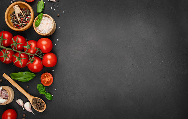 istock Fresh tomatoes, herbs, garlic, and spices arranged on black background with copy space. top view. 2227428800