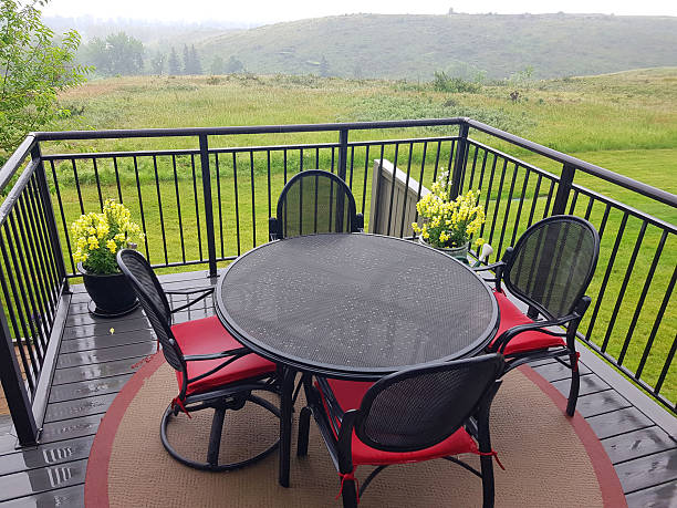 Looking out to residential deck in the rain and seeing beauty.  Pots of Snapdragons.  Water repellent non fading chair cushions. Weather treated patio furniture of table and chairs.