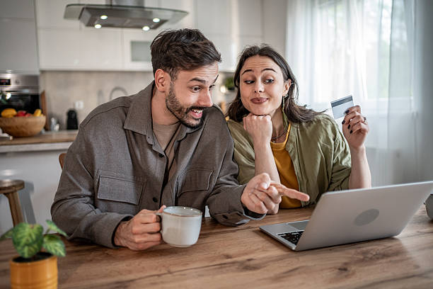 istock Excited couple making online purchases using credit card at home 2227431829