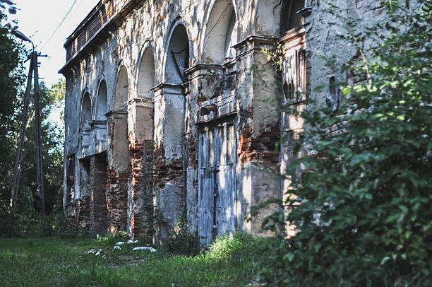 istock Old, Damaged Brick Building Bathed in Sunlight Amidst Green Trees 2227435282