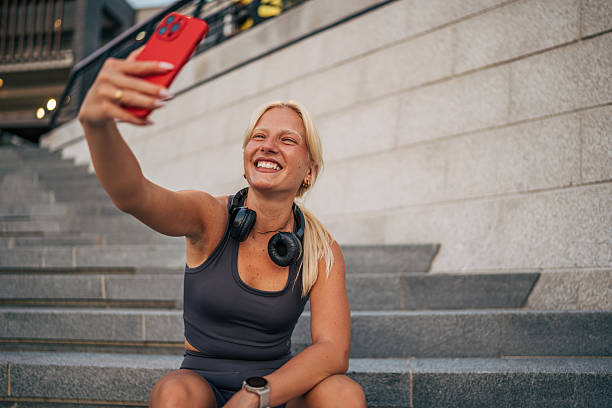 istock Young sporty woman taking a selfie while sitting on urban steps 2227438057