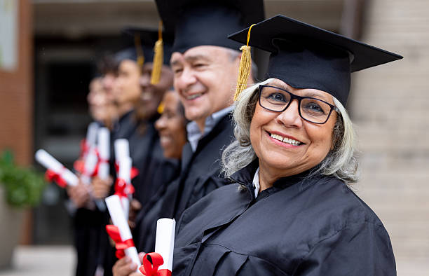 istock Happy senior alumni in a row with her classmates and smiling at the camera 2227445819