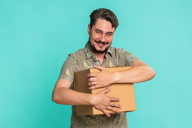 istock Man hugging cardboard delivery box happy smile expressing excitement about received online package 2227453268