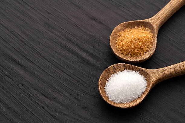 istock Brown sugar and refined white sugar in wooden spoons 2227455778