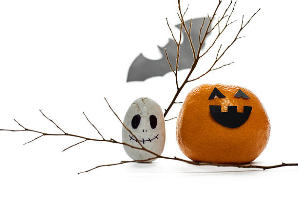 istock Halloween Decorations Featuring Painted Rocks and a Pumpkin on a Bare Branch With a Bat Silhouette 2227459796