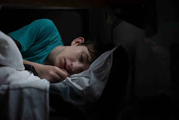 istock teenage boy sleeping on bottom bunk in train at night in darkness 2227460884