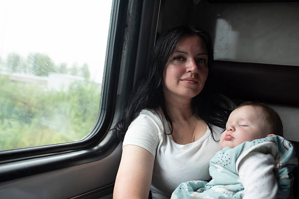 istock a woman with her sleeping baby son sits by the window on a train 2227460920