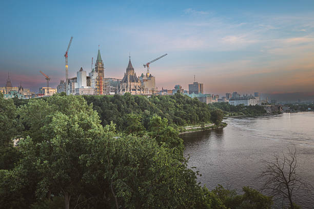 Ottawa, Canada - September, 24, 2024:  A business woman walks next to the Canadian Parliament in Ottawa and checking her mobile phone messages.