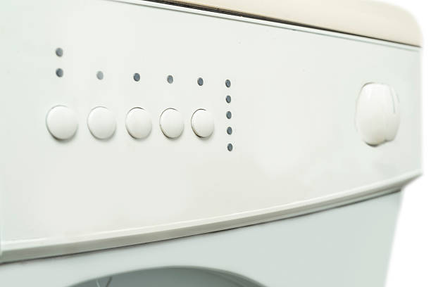 Closeup view of a knob and control panel button on a washing machine. Home appliance