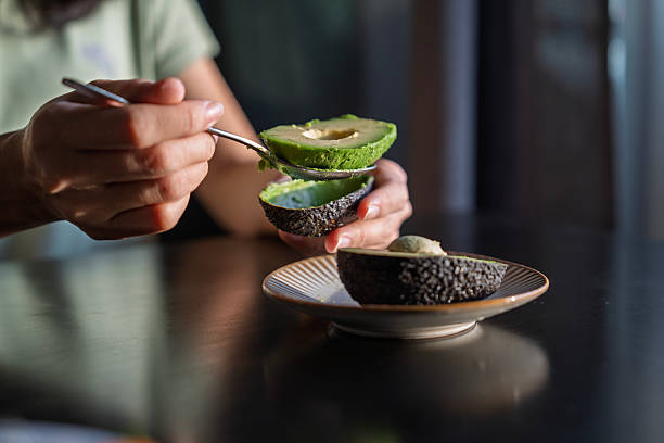 Hands Scooping Fresh Avocado with a Spoon