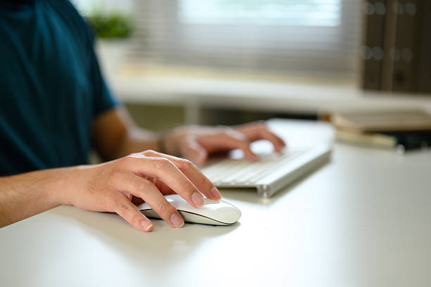istock Close up of person using wireless computer mouse and keyboard on a white desk 2227475801