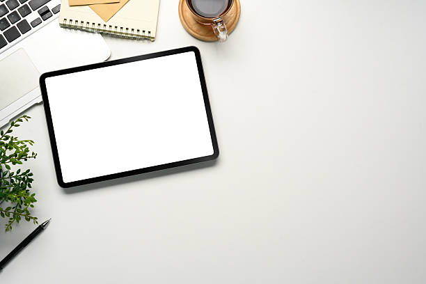 istock Digital tablet with blank screen on clean white desk, surrounded by a laptop and coffee cup 2227475841