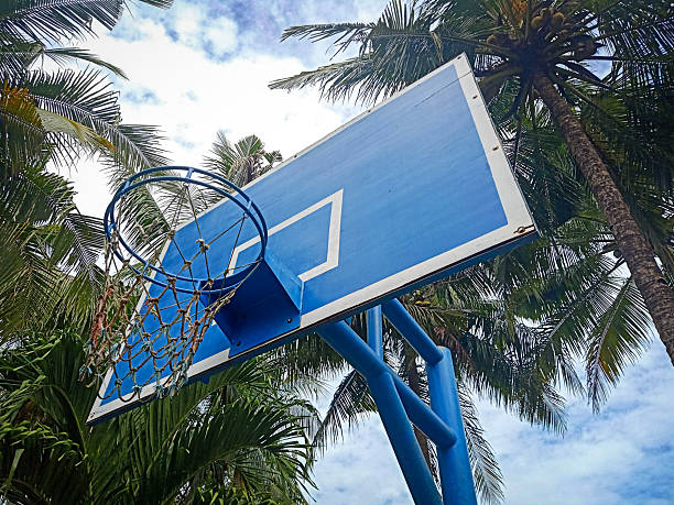 Basketball hoop and blue backboard with cloud sky in background