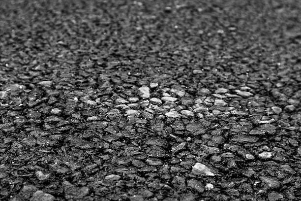 Close-up shot of coarse-grained black asphalt pavement surface, ideal for backgrounds in construction, infrastructure, road safety materials, and architectural mockups.