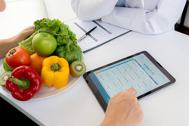 istock Asian nutritionist using tablet to explaining personalized meal plan with AI to patient during healthcare consultation, healthy lifestyle, woman dietitian showing nutrition plan with AI on tablet. 2227480234