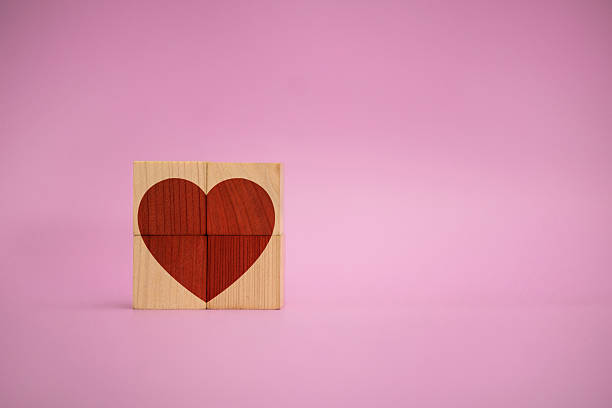 istock Red heart formed from wooden puzzle blocks on pink background 2227482478