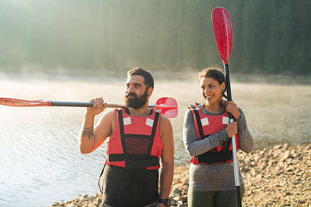 Shot of young couple preparing to go on a kayak adventure in the calm mountain lake in the morning.