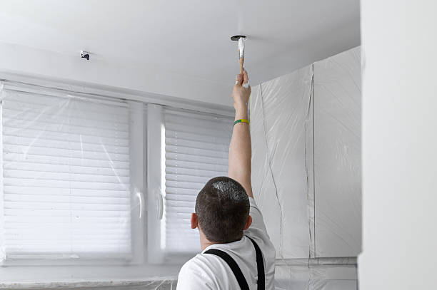 A house painter painting the kitchen ceiling white, renovation