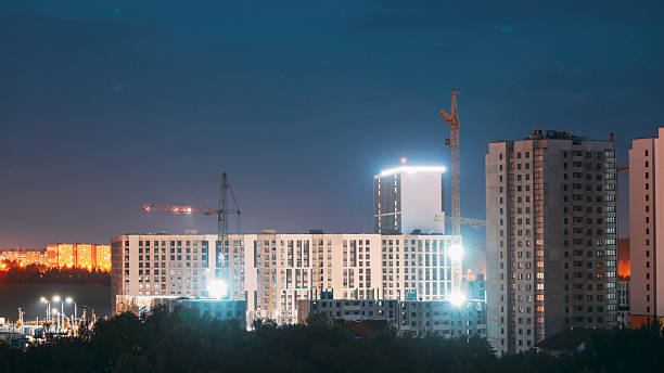 istock night works with construction site area. Development Multistorey Residential Building in night hours. development on construction site. night time work. Construction And Development Of Modern Multi-storey Residential Houses. Night starry sky 2227489122