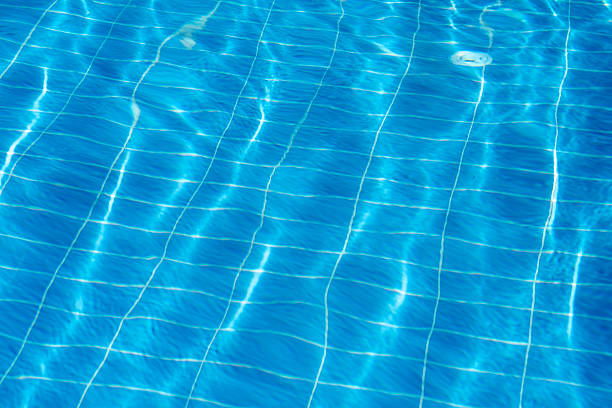 Clear turquoise water fills the swimming pool with sunlight creating shimmering reflections. Perfect for relaxation and leisure during summertime.
