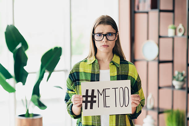 istock Young woman expressing emotional statement about societal issues while holding a handwritten sign indoors in a casual environment 2227494417