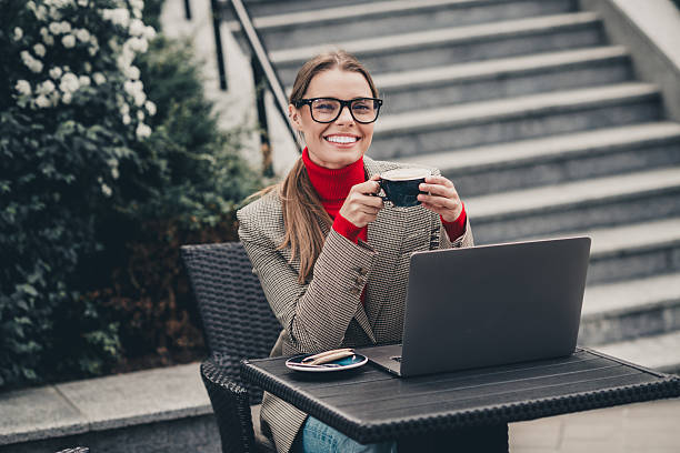 istock Young professional businesswoman enjoying a coffee while working outdoors, showcasing confidence and style in an urban setting 2227496658