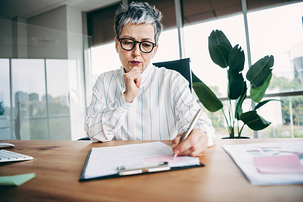 istock Confident mature businesswoman working on professional documents at her elegant modern office desk during a workday 2227497382