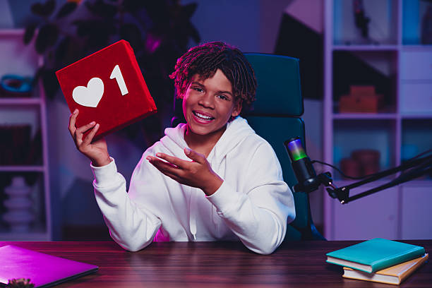 istock Happy man streaming with microphone holding heart-shaped gift in neon-lit studio for social media content creation 2227498129