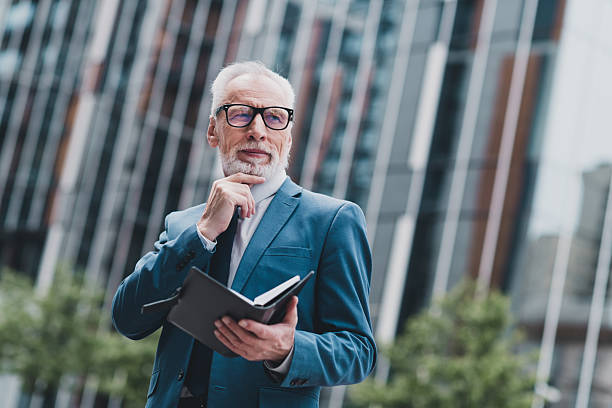 istock Confident senior businessman outdoors, analyzing work on a document in the urban city scene, representing professional success 2227498170