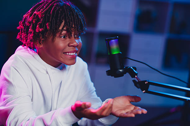 istock Energetic youth vlogger recording content with microphone setup in a neon-lit studio, expressing excitement and enthusiasm 2227498285