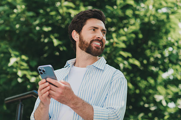 istock Handsome man outdoors holding smartphone and enjoying a sunny urban environment with a positive expression 2227498311