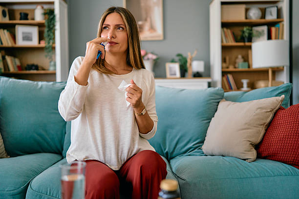 istock Woman applying nasal spray while sitting on sofa at home 2227502999