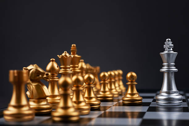istock King silver chess standing confront of the golden chess team. 2227505318