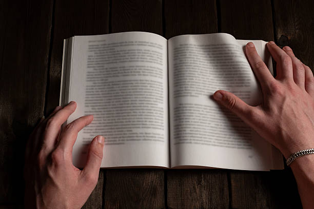 istock Hands holding open book on dark wooden table 2227505334