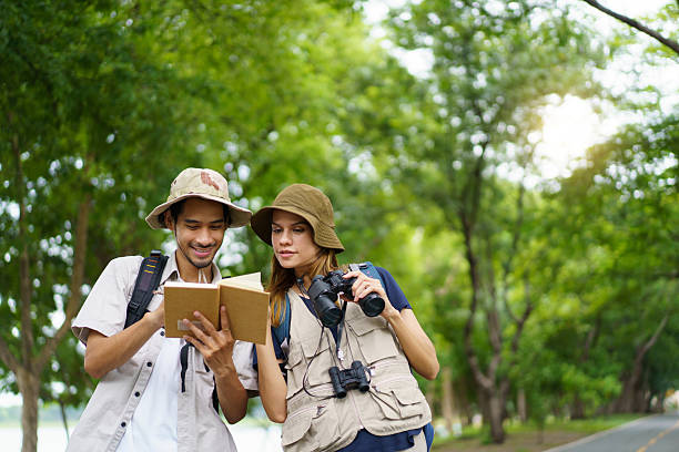 istock Man and woman joyfully birdwatching activity in a park. They study about bird watching. 2227505762