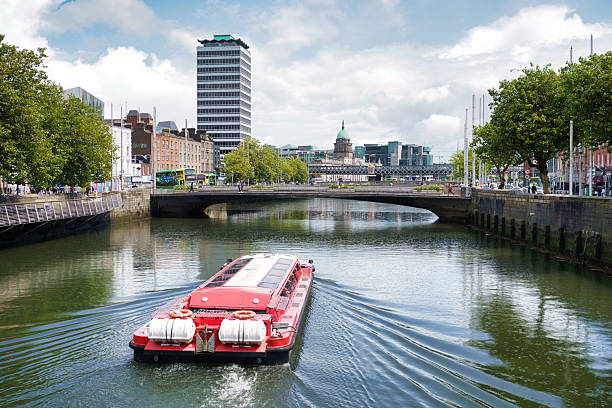 A vibrant shot of Dublin, Ireland, capturing the River Liffey with a tourist boat, bridges, and cityscapes under a bright sky.
