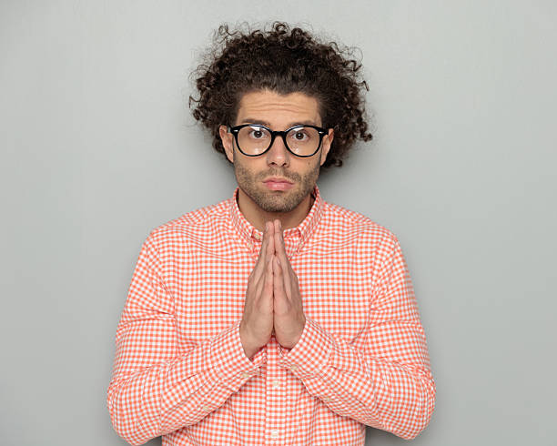 istock serious young man with glasses looking forward and praying for a miracle 2227509259